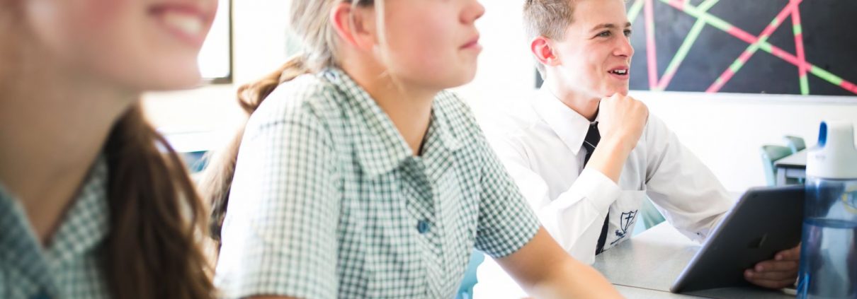 Three students smiling and looking up in class.