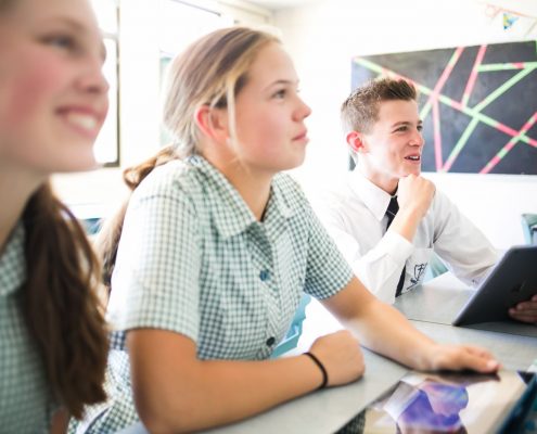 Three students smiling and looking up in class.